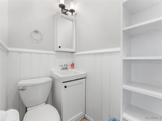 bathroom featuring wainscoting, toilet, and vanity