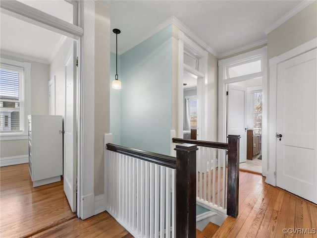 hallway featuring hardwood / wood-style flooring, an upstairs landing, baseboards, and ornamental molding