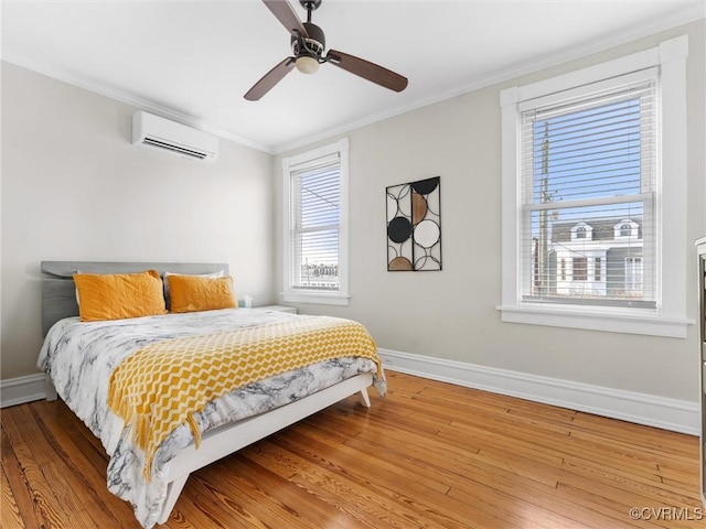 bedroom featuring baseboards, light wood-type flooring, crown molding, and a wall unit AC