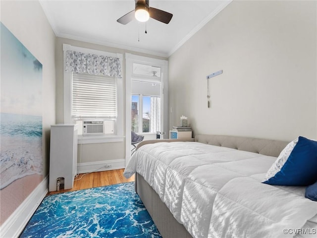 bedroom with cooling unit, wood finished floors, baseboards, and ornamental molding