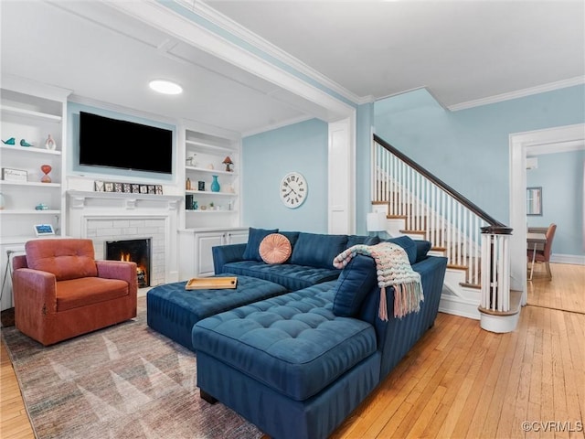 living area with stairs, light wood-style flooring, a fireplace, and ornamental molding