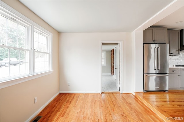 interior space featuring light wood finished floors, visible vents, high end fridge, and decorative backsplash