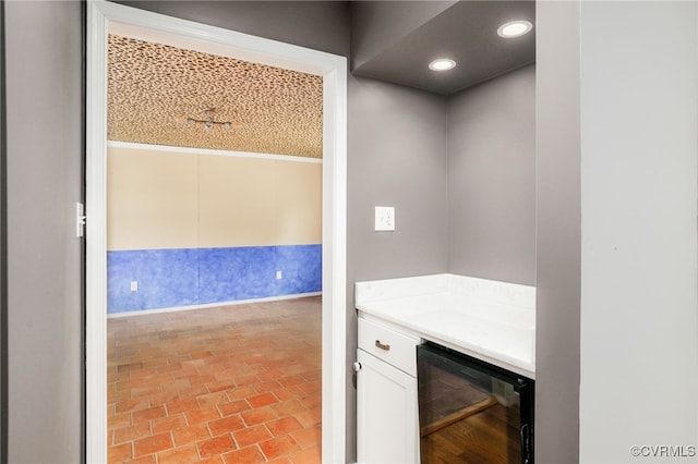 bar with wine cooler, recessed lighting, and brick floor