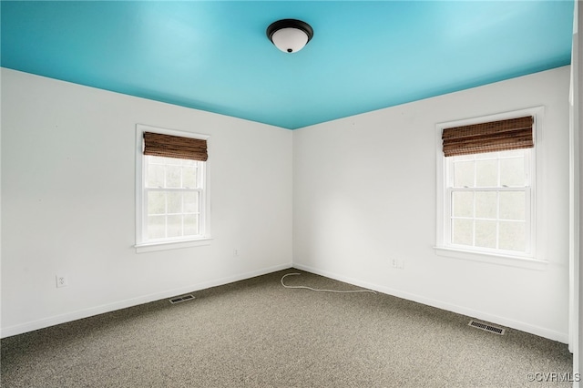 carpeted spare room featuring visible vents and baseboards