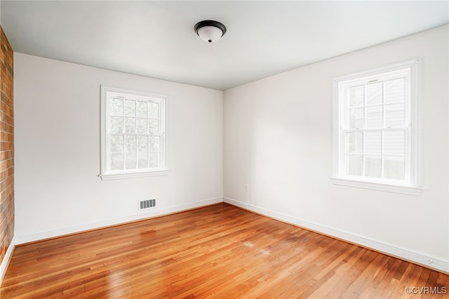 unfurnished room featuring visible vents, light wood-style flooring, and baseboards