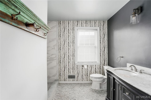 bathroom featuring tiled shower, toilet, and vanity