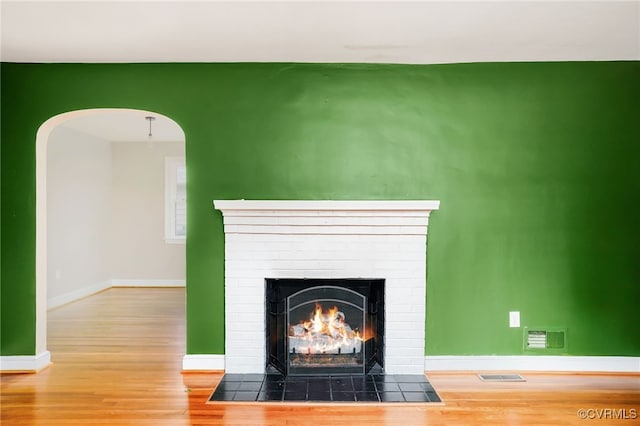 interior details with visible vents, arched walkways, wood finished floors, and a fireplace