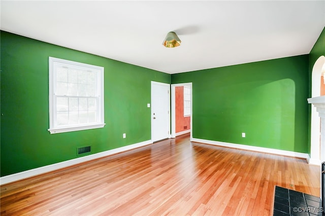 spare room featuring visible vents, baseboards, arched walkways, and wood finished floors