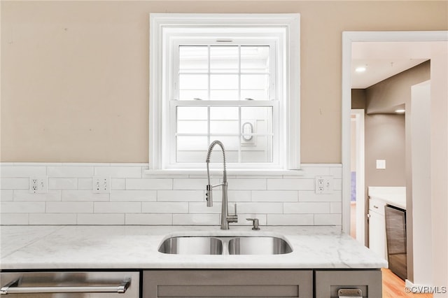 kitchen featuring dishwashing machine, gray cabinets, and a sink