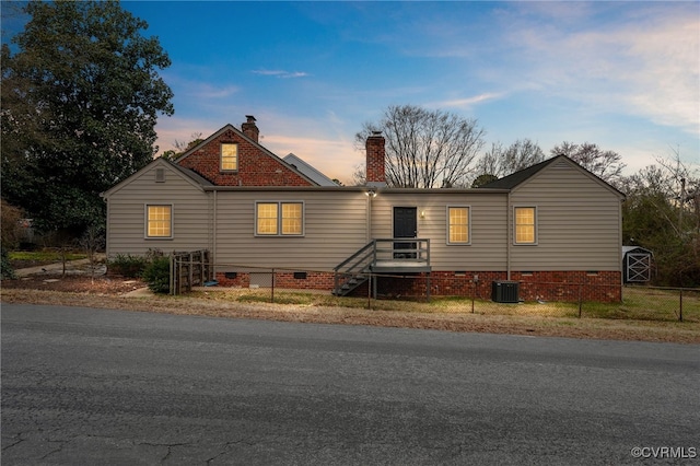 view of front of property with fence private yard, a chimney, central AC, and crawl space