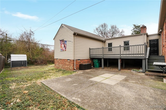 rear view of house with an outdoor structure, crawl space, a deck, a storage shed, and a lawn