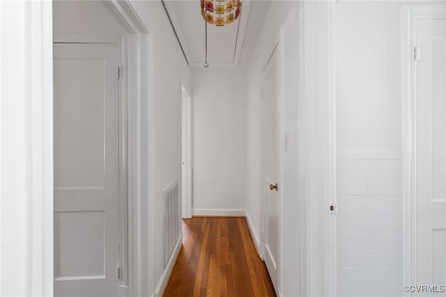 corridor with baseboards, attic access, dark wood-style flooring, and visible vents