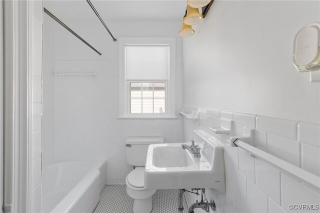 full bath with tile walls, a sink, tile patterned floors, a wainscoted wall, and toilet