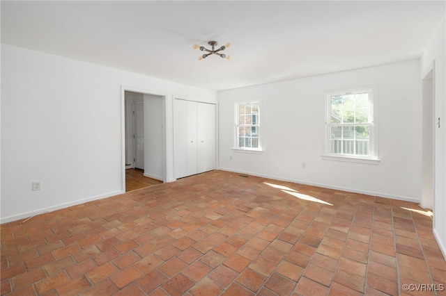 empty room with baseboards and brick floor