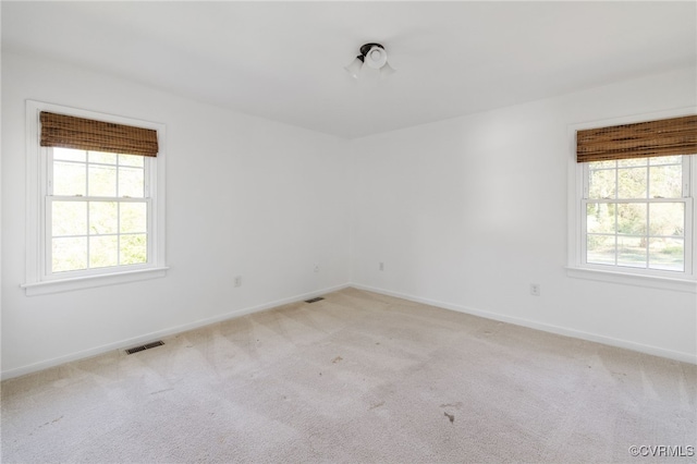 spare room with visible vents, baseboards, and light colored carpet