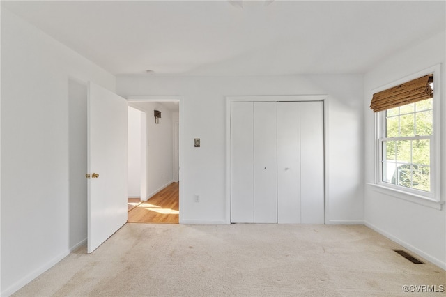unfurnished bedroom featuring baseboards, visible vents, carpet, and a closet
