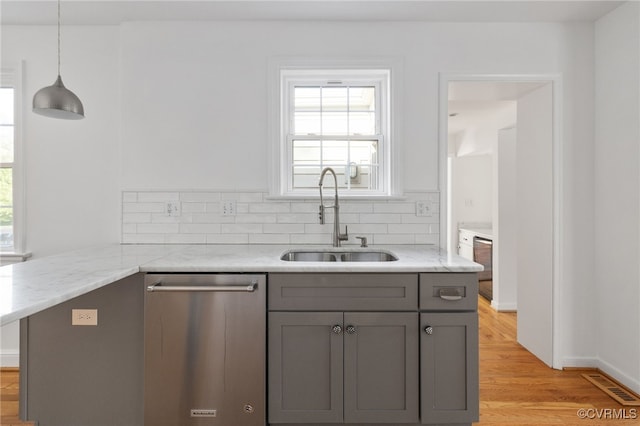 kitchen featuring light stone countertops, a sink, dishwasher, gray cabinets, and visible vents