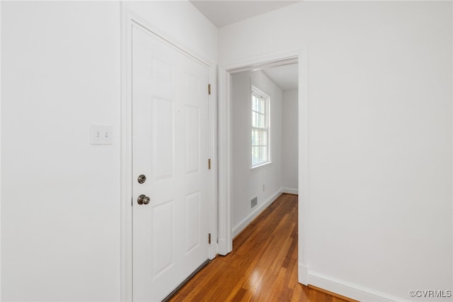 corridor with light wood-style floors, baseboards, and visible vents