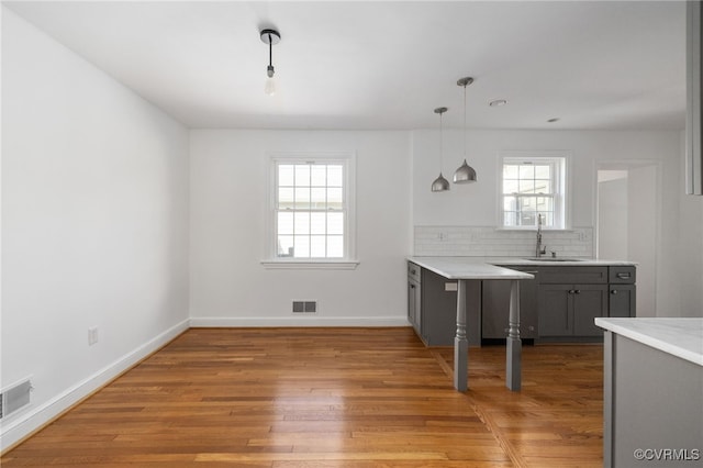 kitchen featuring visible vents, a sink, a healthy amount of sunlight, and gray cabinetry