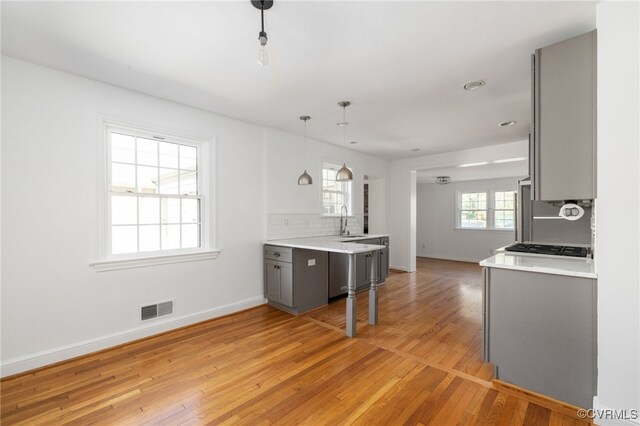 kitchen with visible vents, baseboards, light countertops, a sink, and gray cabinetry