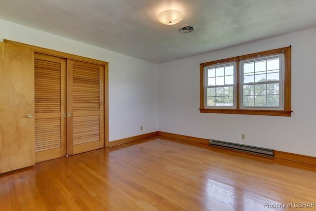 unfurnished bedroom featuring light wood-style floors, visible vents, a closet, and a baseboard radiator