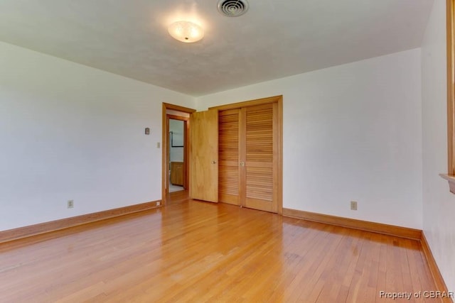 unfurnished bedroom featuring light wood-type flooring, visible vents, baseboards, and a closet