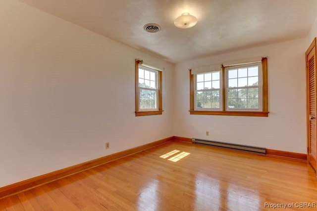 unfurnished room with light wood-style flooring, visible vents, baseboards, and baseboard heating