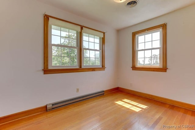 spare room with baseboards, visible vents, baseboard heating, and light wood-type flooring