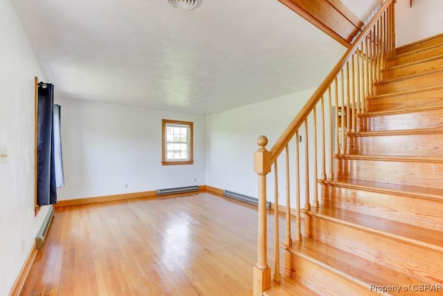 stairway with baseboard heating, baseboards, and wood finished floors