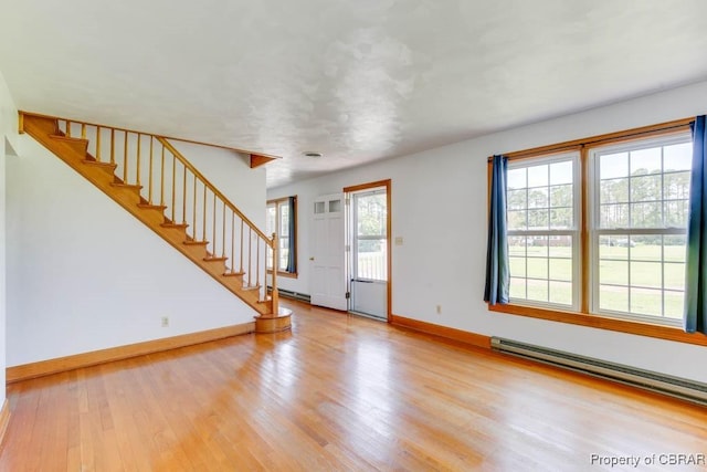 interior space featuring wood finished floors, stairs, baseboards, and a baseboard radiator