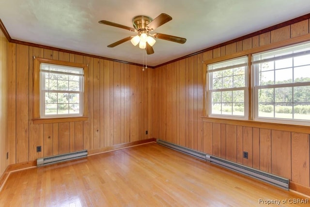 spare room featuring ceiling fan, a baseboard radiator, wooden walls, and light wood-style flooring