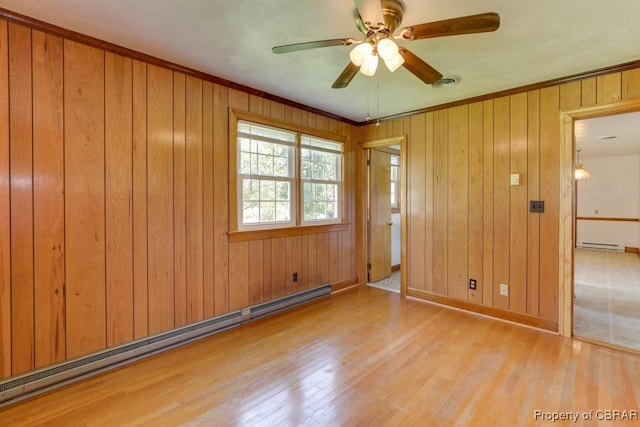 spare room featuring baseboard heating, ceiling fan, visible vents, and wood finished floors