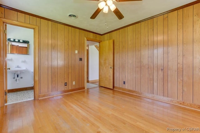 unfurnished room featuring visible vents, wood finished floors, wood walls, crown molding, and baseboards