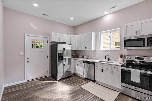 kitchen featuring visible vents, dark wood-type flooring, a sink, stainless steel appliances, and light countertops