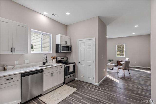 kitchen featuring visible vents, white cabinets, stainless steel appliances, and a sink