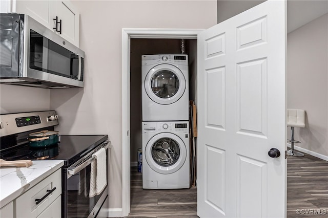 washroom featuring baseboards, dark wood-style floors, laundry area, and stacked washer / dryer