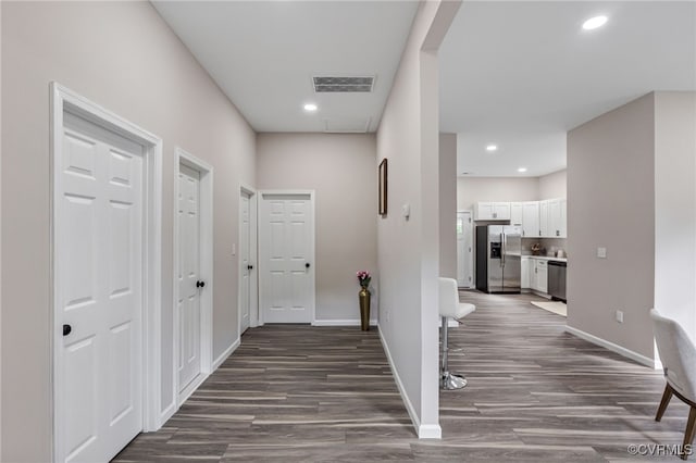 hallway featuring dark wood finished floors, recessed lighting, baseboards, and visible vents