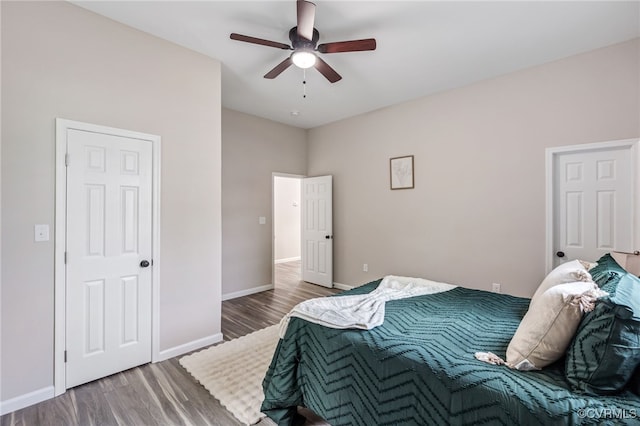 bedroom featuring baseboards, wood finished floors, and a ceiling fan