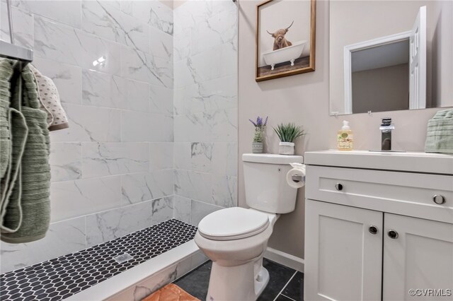 bathroom with baseboards, vanity, a shower stall, and toilet