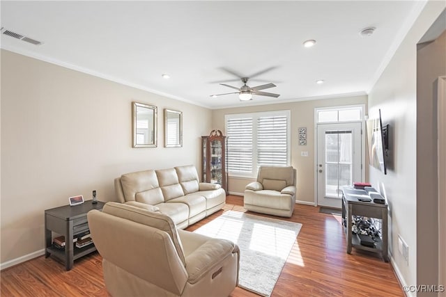 living area with visible vents, ceiling fan, baseboards, ornamental molding, and wood finished floors