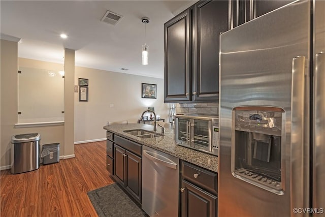 kitchen with visible vents, dark wood-type flooring, dark stone countertops, appliances with stainless steel finishes, and a sink