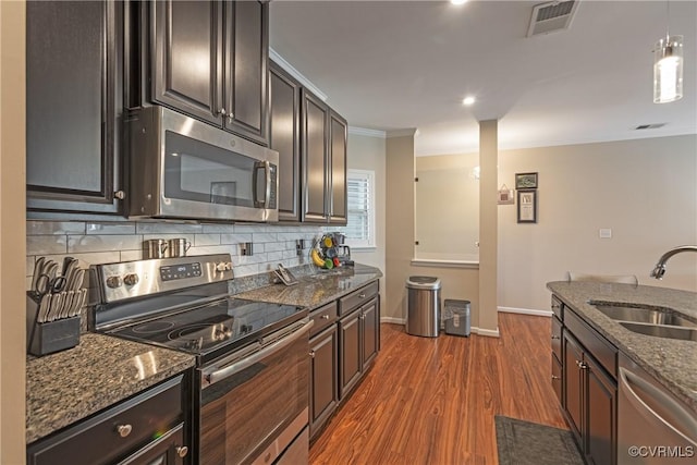 kitchen featuring dark wood-style floors, visible vents, a sink, stainless steel appliances, and backsplash