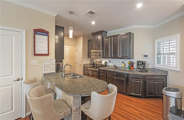 kitchen featuring visible vents, a breakfast bar area, light wood-style flooring, appliances with stainless steel finishes, and a sink