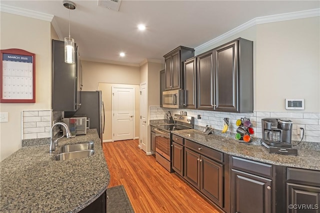 kitchen featuring light wood-style flooring, a sink, decorative backsplash, ornamental molding, and stainless steel appliances