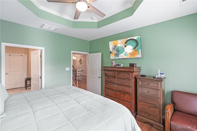 bedroom featuring ceiling fan, visible vents, a raised ceiling, and ornamental molding