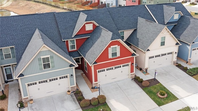 view of front of house with driveway, roof with shingles, a garage, board and batten siding, and a residential view