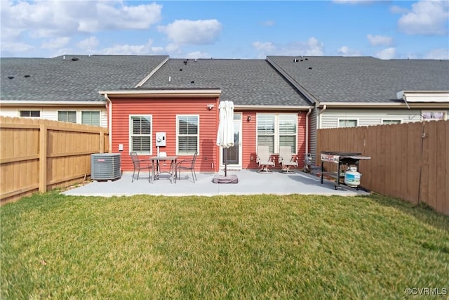 rear view of property featuring a lawn, a fenced backyard, a shingled roof, central AC unit, and a patio area