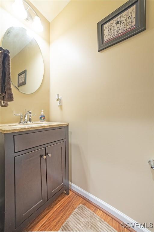 bathroom featuring vanity, wood finished floors, and baseboards