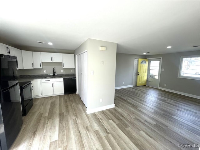 kitchen featuring a sink, light wood-style flooring, black appliances, and open floor plan