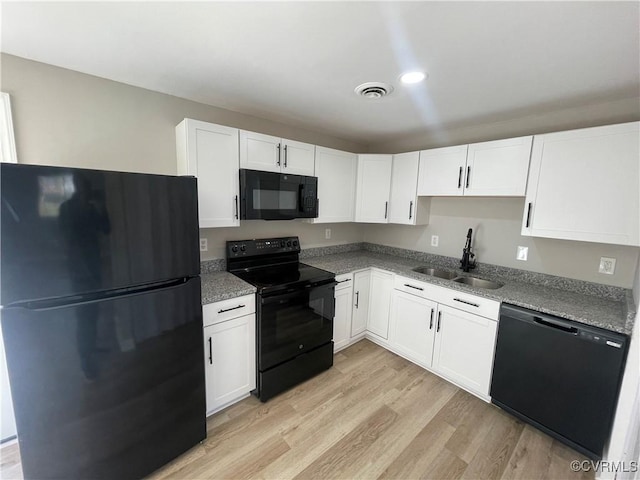 kitchen featuring a sink, visible vents, black appliances, and white cabinetry